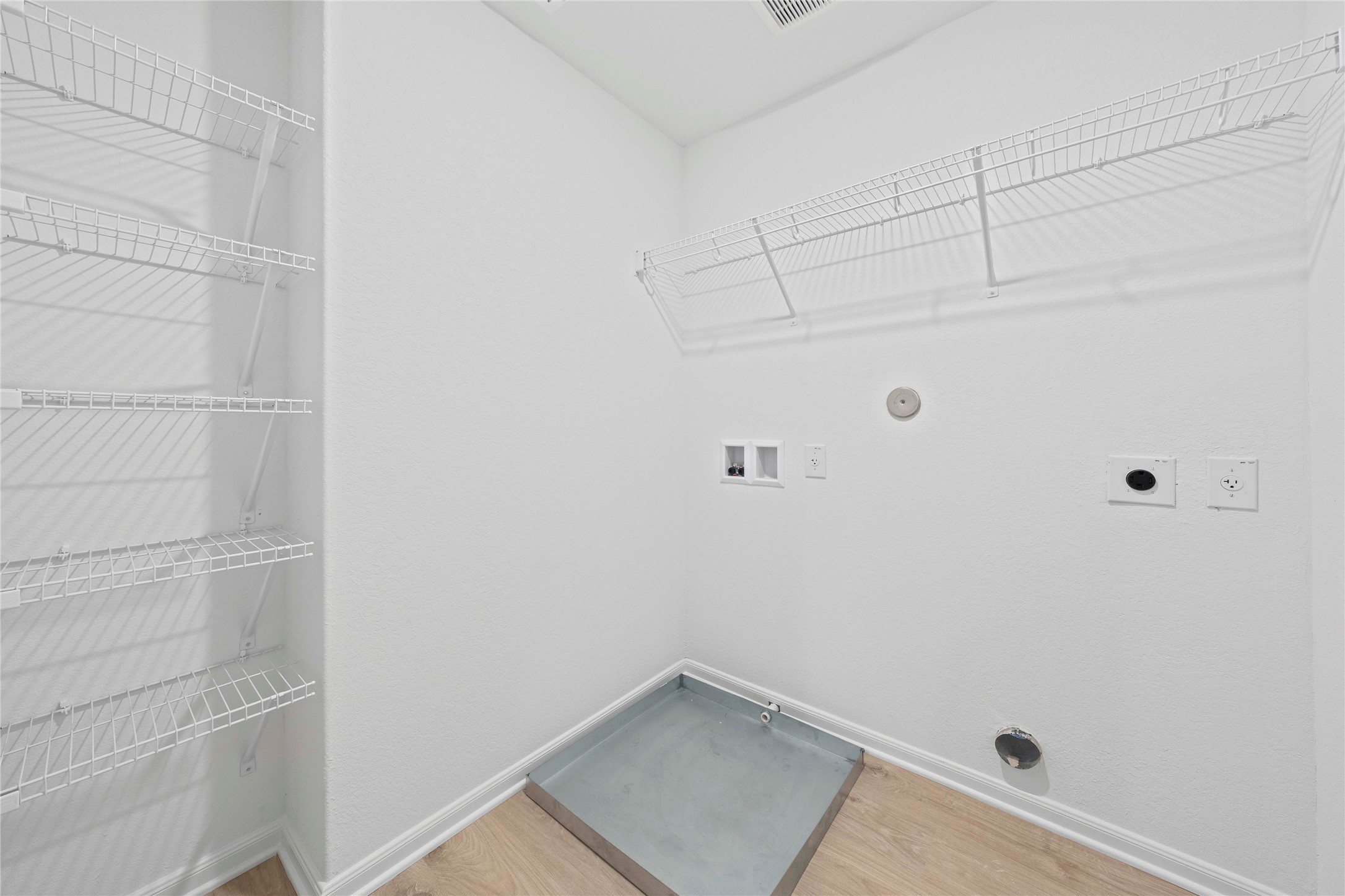 237 Fairlawn Way Maxwell, TX 78656 - Photo 12 of 12 Utility area with white wire shelving, a metal drain pan, and wood-style flooring