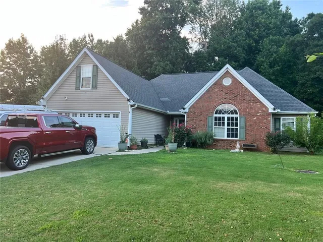 a front view of a house with a garden and trees