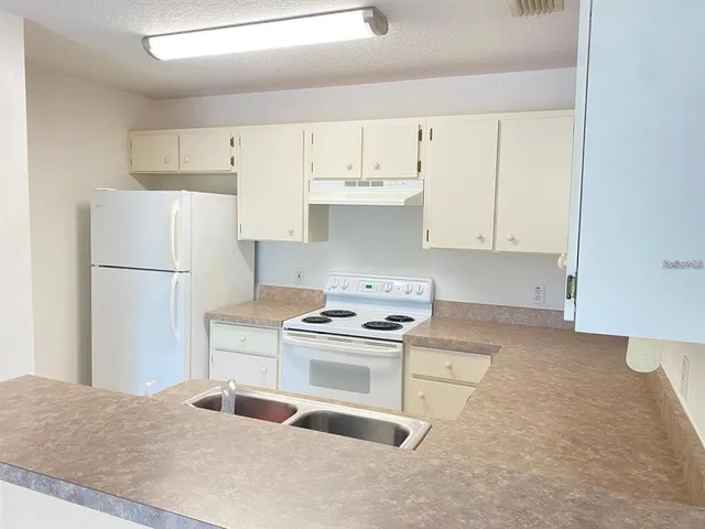 a kitchen with granite countertop a sink stove and refrigerator
