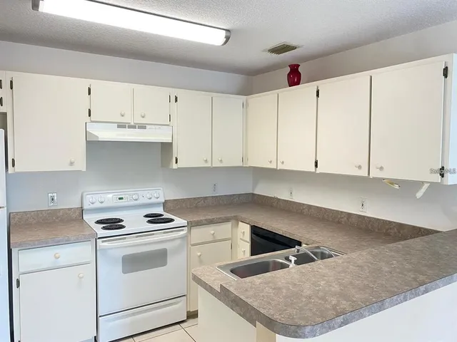 a kitchen with granite countertop white cabinets and white appliances