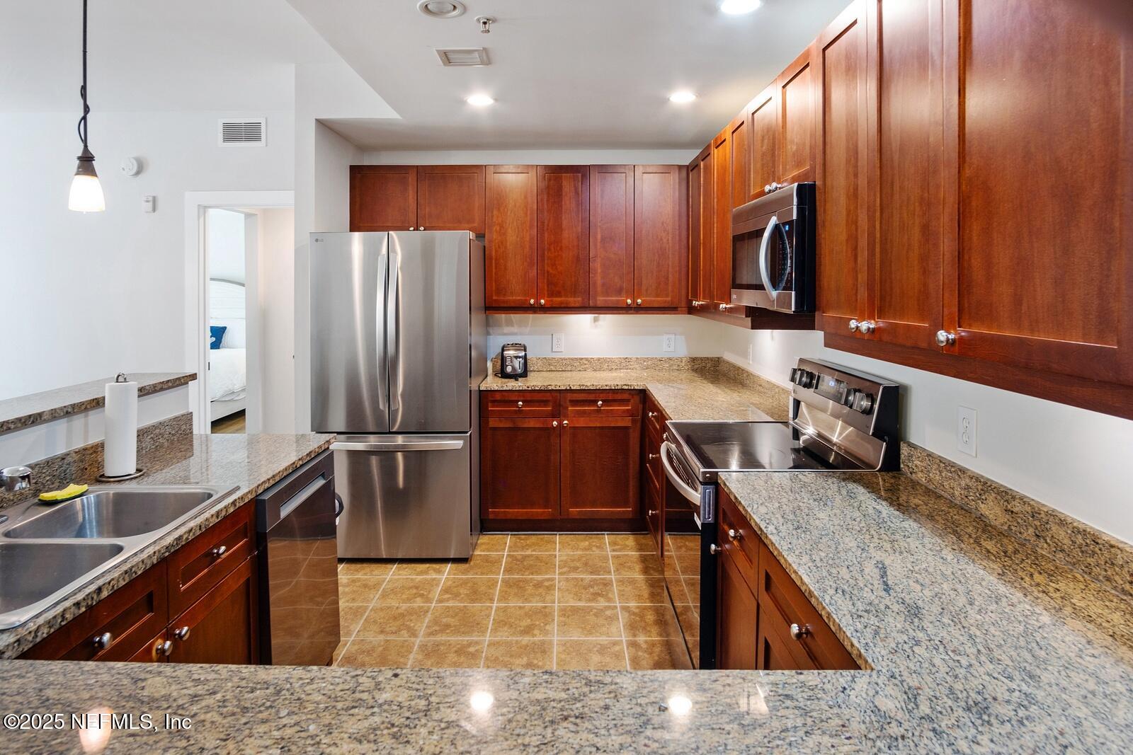 945 Registry Boulevard, Unit 210 St. Augustine, FL 32092 - Photo 4 of 28 a kitchen with stainless steel appliances granite countertop a sink stove and refrigerator