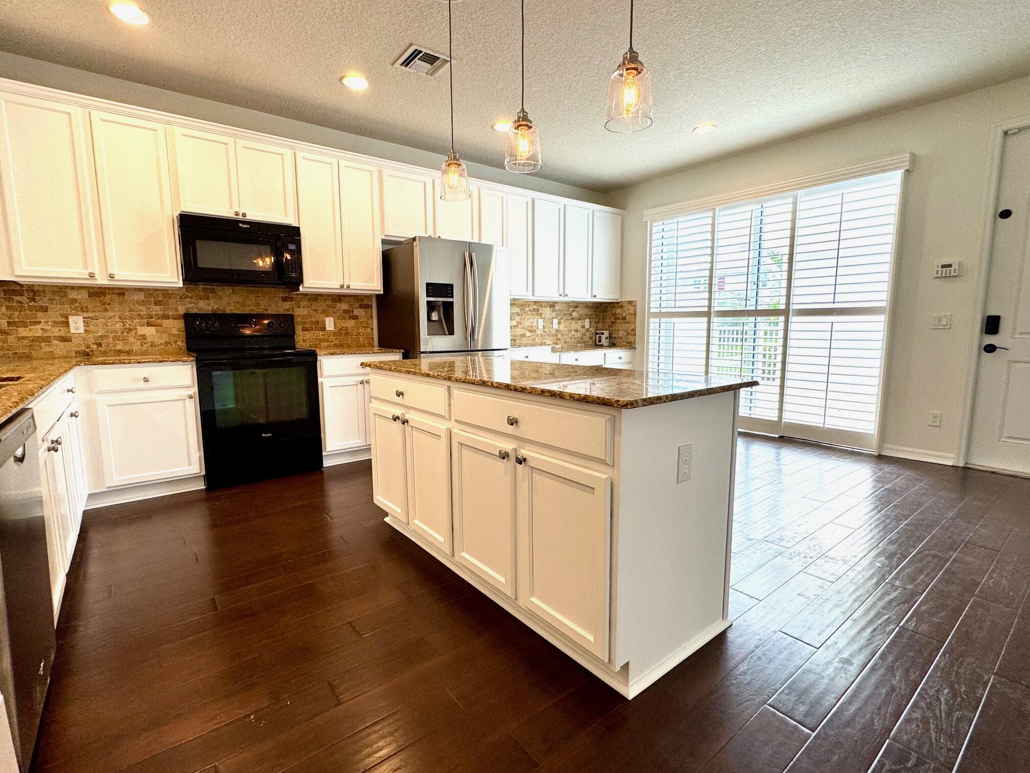 1346 Turnbridge Drive Jupiter, FL 33458 - Photo 10 of 46 a kitchen with stainless steel appliances granite countertop a stove top oven a sink dishwasher a refrigerator and a microwave