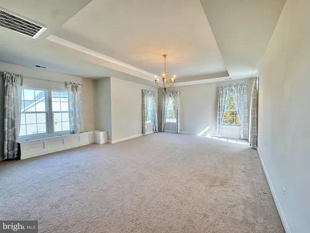 a view of an empty room with window and chandelier