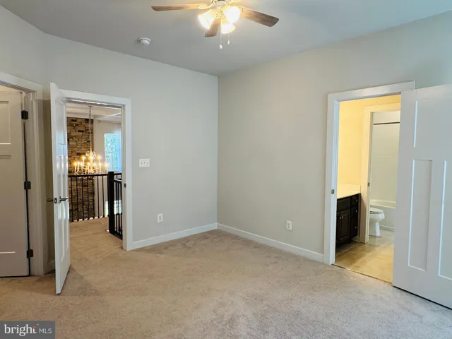an empty room with chandelier fan and windows