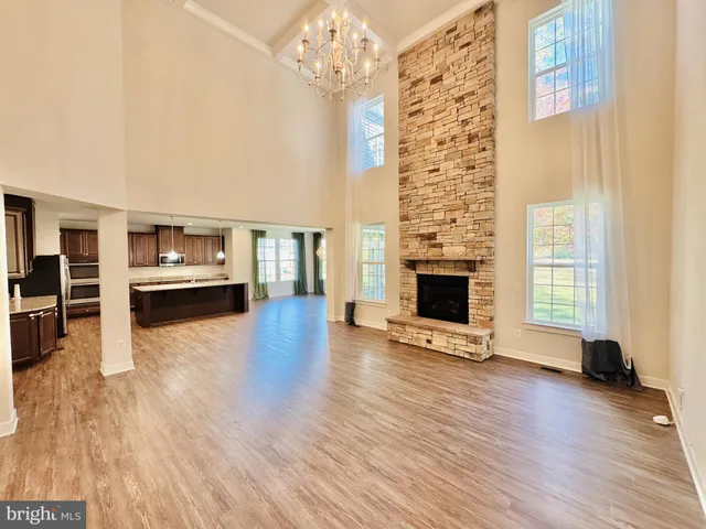 a view of a livingroom with wooden floor a ceiling fan and windows