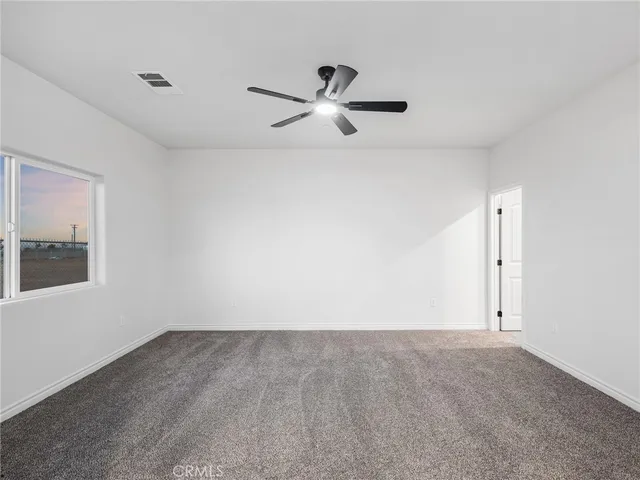 an empty room with a ceiling fan and window