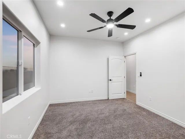 an empty room with ceiling fan and windows
