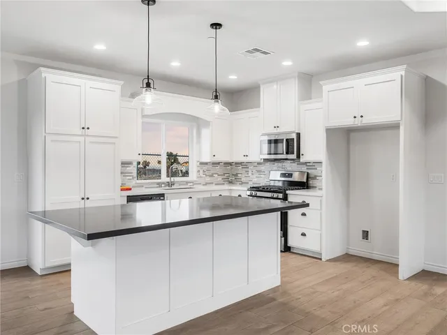 a kitchen with kitchen island granite countertop a sink a center island a stove and a refrigerator