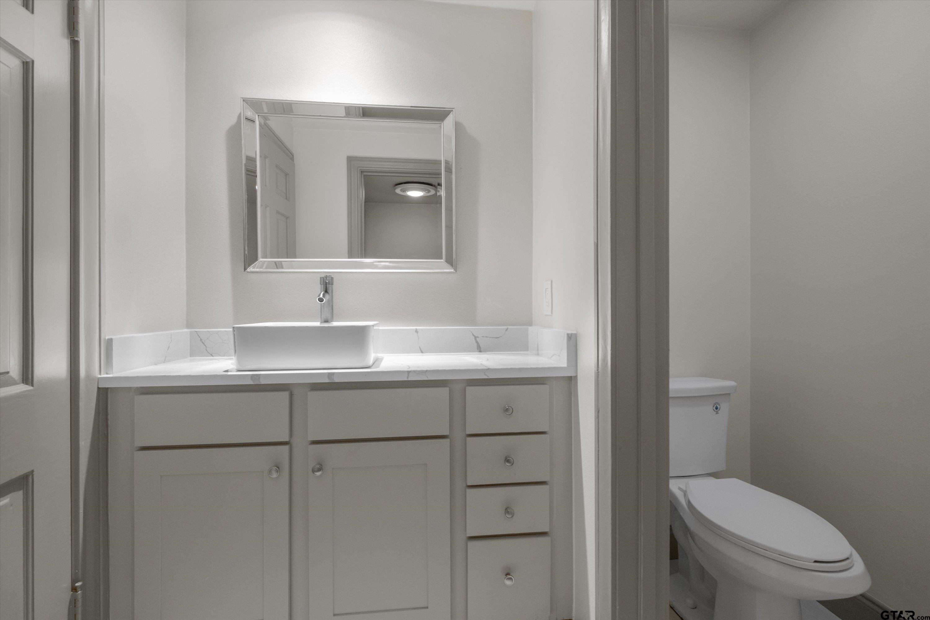 2126 McDonald Road Tyler, TX 75701 - Photo 11 of 26 a bathroom with a toilet a sink and mirror