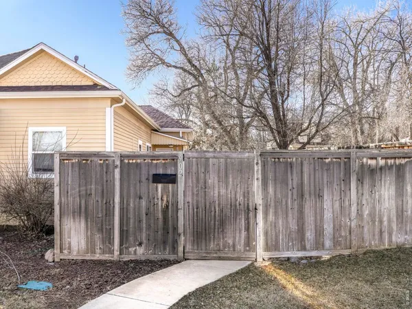a view of a house with wooden fence next to a small yard