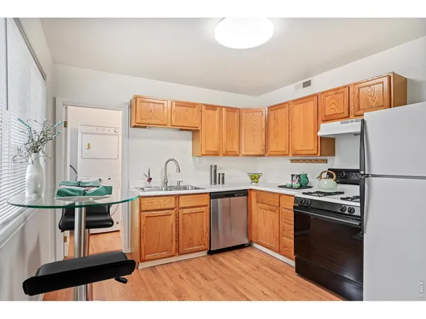 a kitchen with stainless steel appliances a sink a stove a refrigerator cabinets and a window