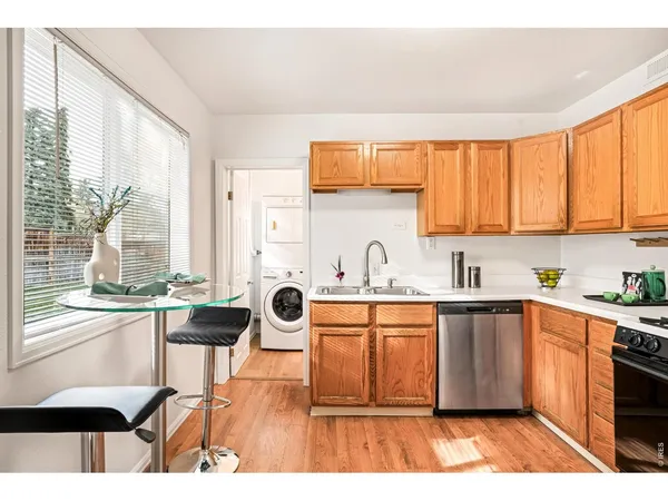 a kitchen with stainless steel appliances a stove a sink and white cabinets with wooden floor
