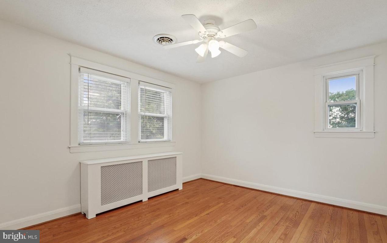 7844 St Thomas Drive Baltimore, MD 21236 - Photo 2 of 5 an empty room with wooden floor chandelier fan and windows