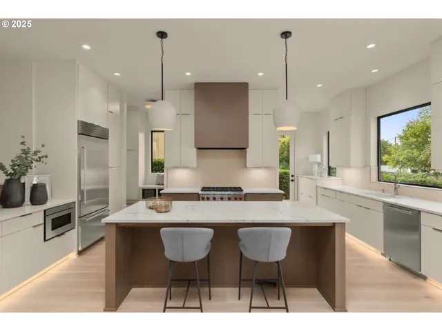 a kitchen with stainless steel appliances kitchen island granite countertop a sink a stove a refrigerator and island with wooden floor