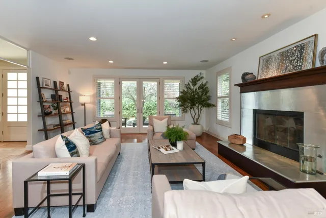 a living room with furniture potted plant a fireplace and a large window