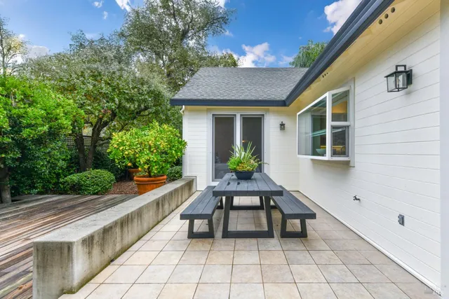a view of house with seating space and trees in the background