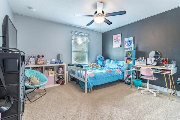 a bedroom with a bed a desk and a chandelier