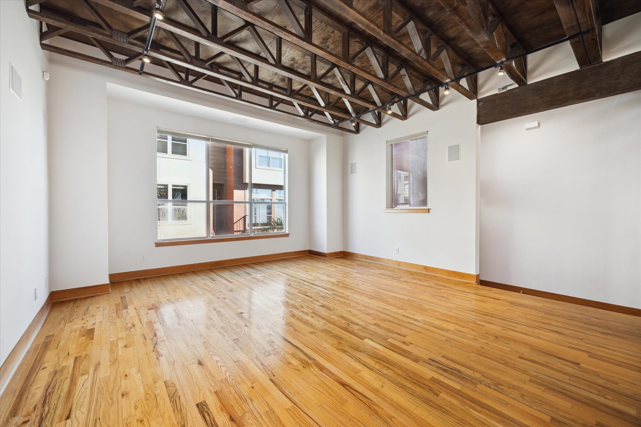 94 Drew Street, Unit C Houston, TX 77006 - Photo 9 of 29 Industrial-style space featuring featuring 10' ceilings with exposed stained trusses and hardwood flooring.