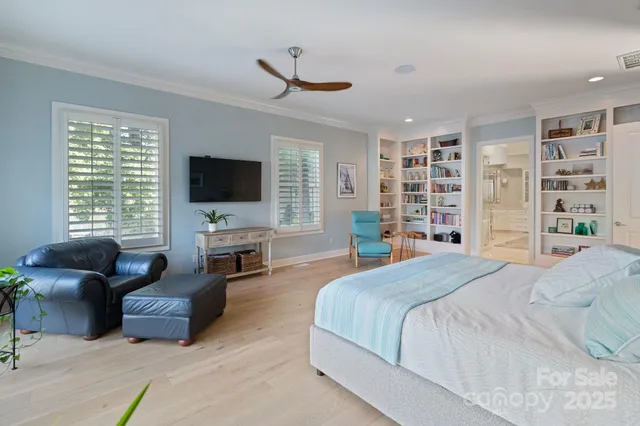 a spacious bedroom with a bed a flat screen tv and dresser