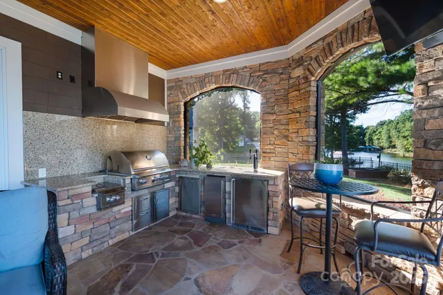 a open kitchen with stainless steel appliances granite countertop a stove a table and chairs in it
