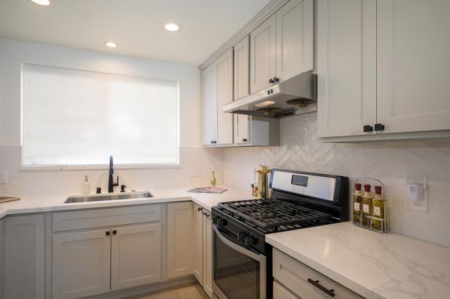 a kitchen with stainless steel appliances granite countertop a sink stove and cabinets