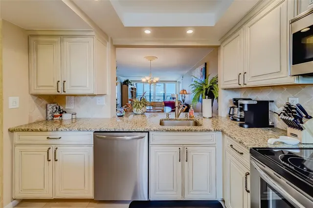 a kitchen with stainless steel appliances granite countertop a sink dishwasher stove and refrigerator with wooden floor