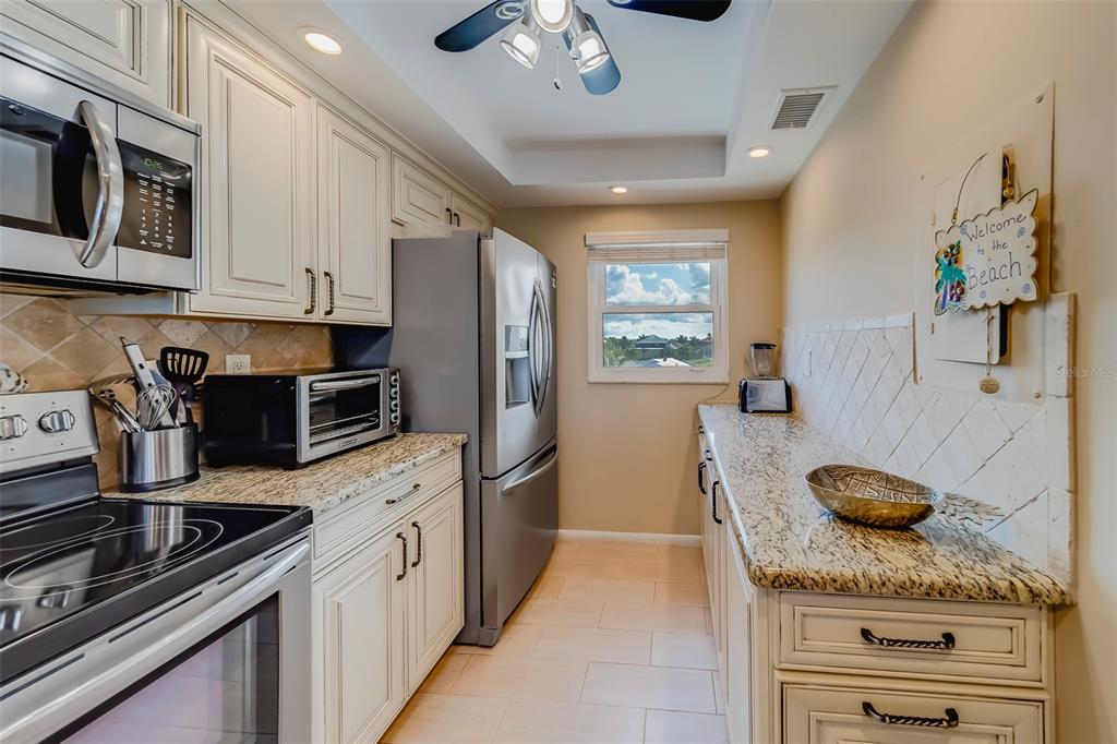 17580 Gulf Boulevard, Unit 412 Redington Shores, FL 33708 - Photo 20 of 67 a kitchen with stainless steel appliances granite countertop a sink dishwasher stove and refrigerator with wooden floor
