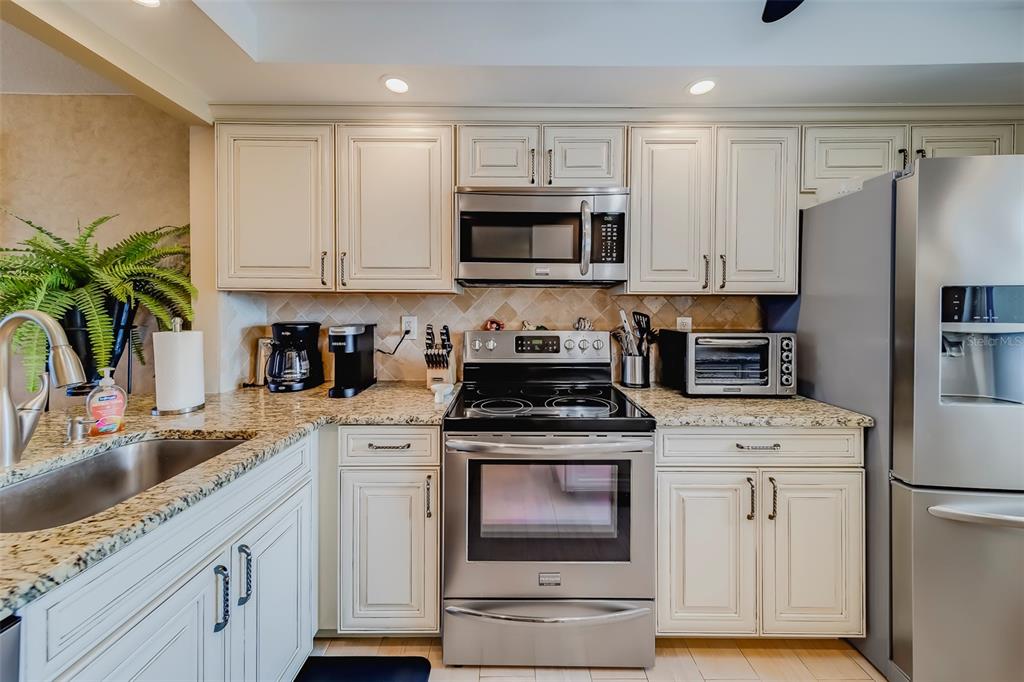 17580 Gulf Boulevard, Unit 412 Redington Shores, FL 33708 - Photo 21 of 67 a kitchen with white cabinets and white appliances