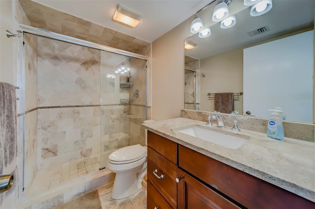 17580 Gulf Boulevard, Unit 412 Redington Shores, FL 33708 - Photo 30 of 67 a bathroom with a granite countertop sink a toilet a mirror and shower