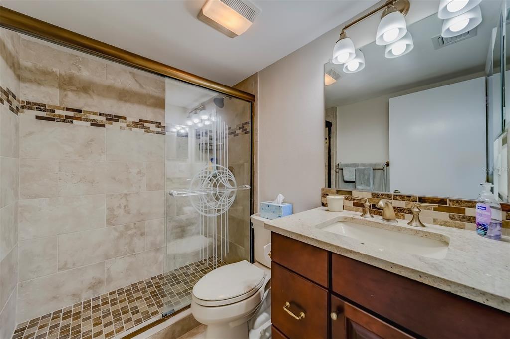17580 Gulf Boulevard, Unit 412 Redington Shores, FL 33708 - Photo 37 of 67 a bathroom with a sink vanity granite toilet and shower