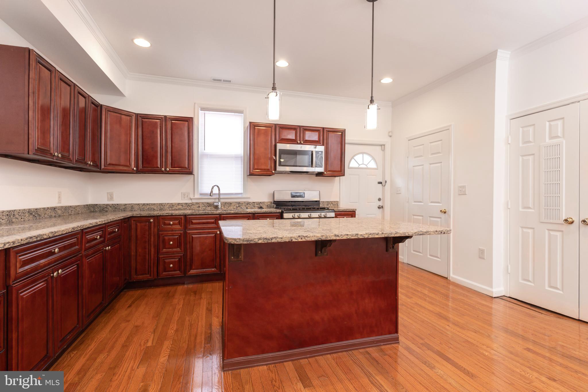 1911 17th Street Southeast Washington, DC 20020 - Photo 3 of 44 a kitchen with stainless steel appliances granite countertop wooden cabinets a stove a sink and a wooden floor