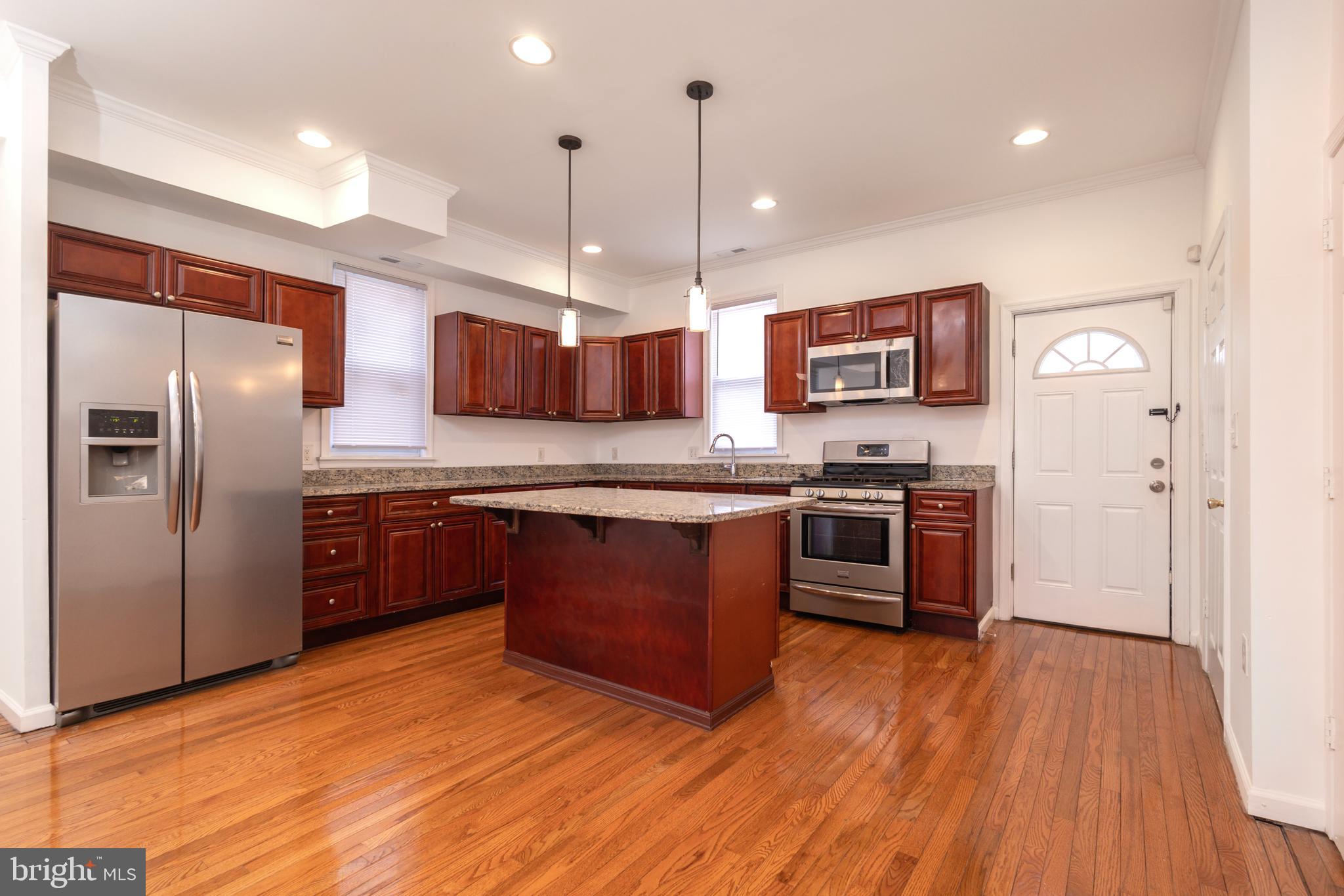 1911 17th Street Southeast Washington, DC 20020 - Photo 4 of 44 a kitchen with stainless steel appliances granite countertop a stove a sink dishwasher a refrigerator and a wooden floor