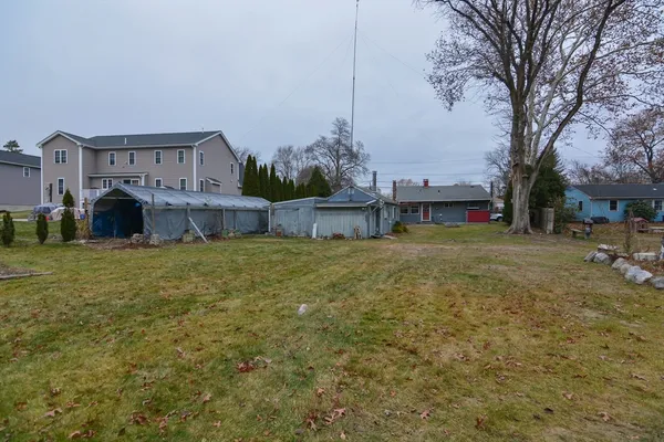 a view of a house with a yard and a large tree