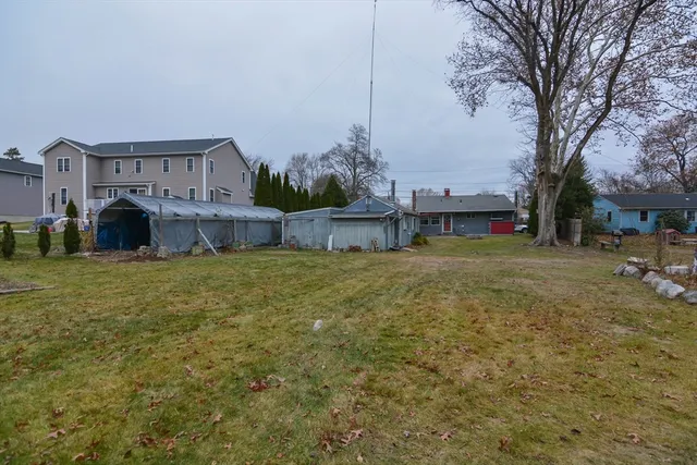 a view of a house with a yard and a large tree