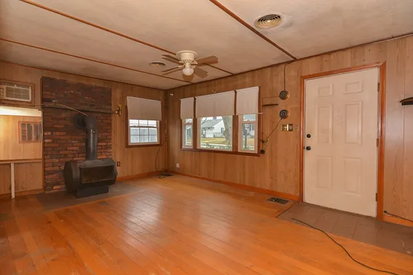 an empty room with windows chandelier fan and windows