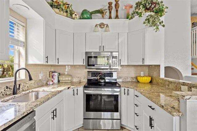 a kitchen with granite countertop a sink stainless steel appliances and cabinets