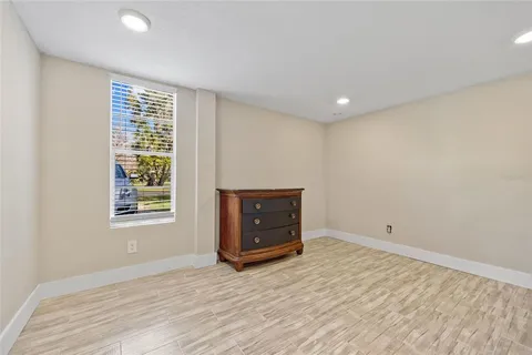 a view of an empty room with a window and wooden floor