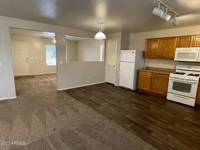a view of a kitchen with a sink stove cabinets and empty room