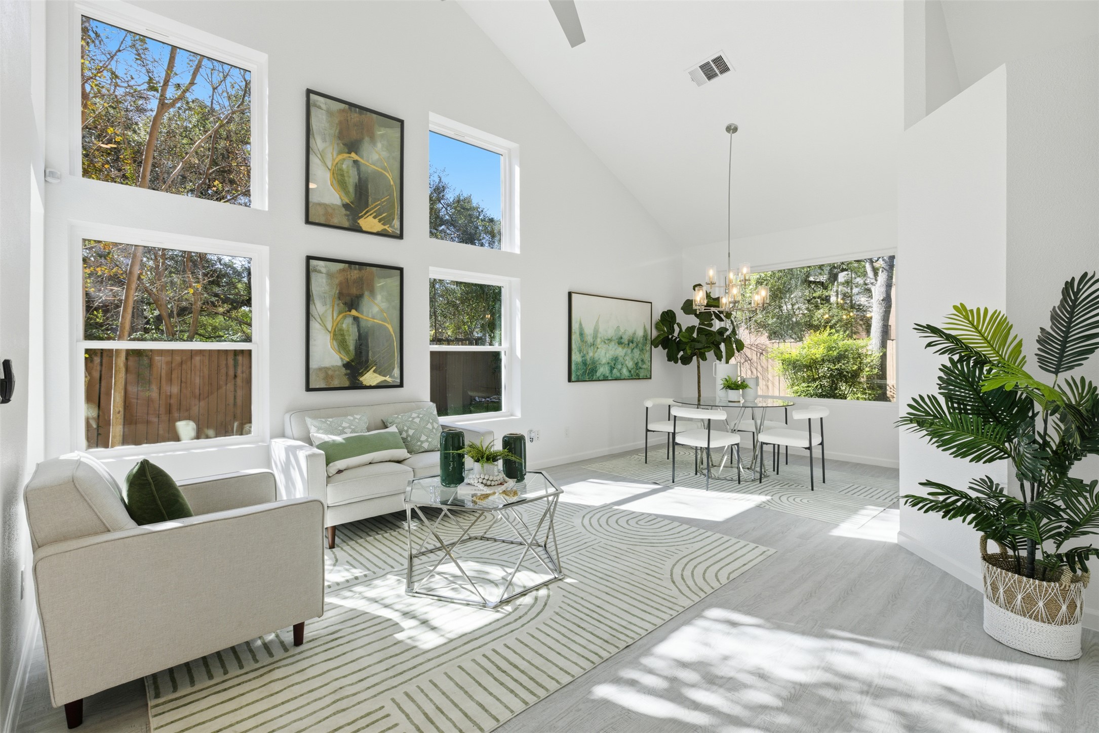 Living area featuring high vaulted ceiling, wood finished floors, healthy amount of natural light, and a chandelier