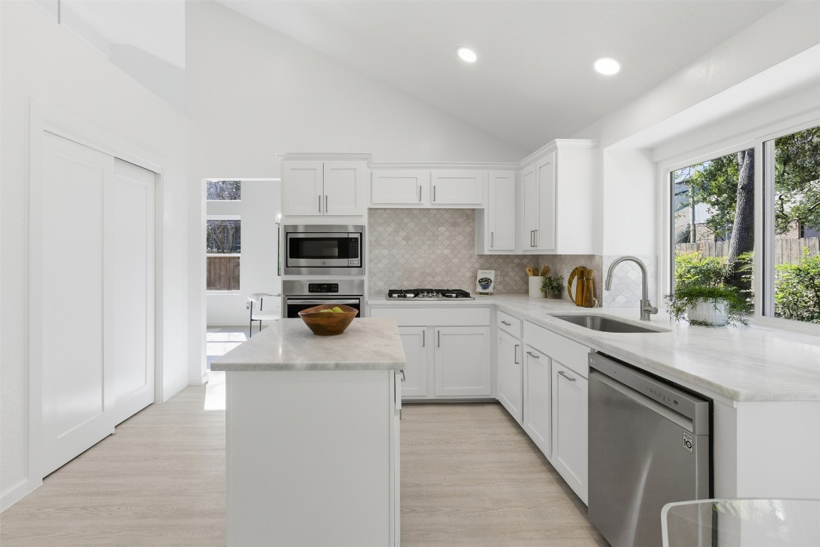 10902 Wareham Court Austin, TX 78739 - Photo 14 of 37 Kitchen featuring white cabinets, decorative backsplash, appliances with stainless steel finishes, a center island, and recessed lighting