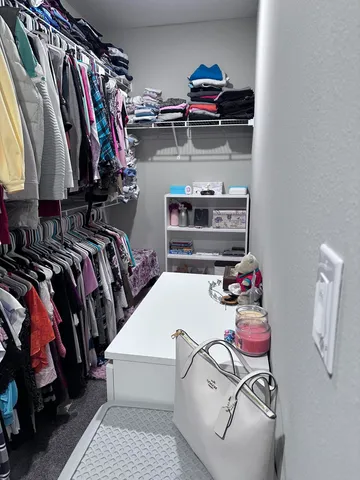 a view of walk in closet with clothes and shoes