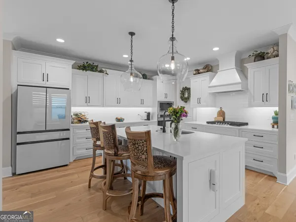 a kitchen with stainless steel appliances kitchen island granite countertop a table chairs and a refrigerator