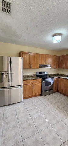 a kitchen with stainless steel appliances granite countertop a stove top oven a sink and a refrigerator