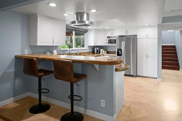 a kitchen with stainless steel appliances a sink a stove a refrigerator cabinets and dining table