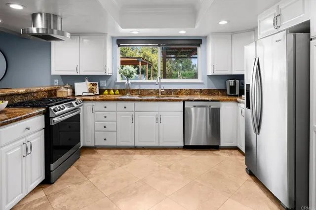 a kitchen with stainless steel appliances granite countertop a stove a refrigerator with a sink and dishwasher a refrigerator with wooden cabinets