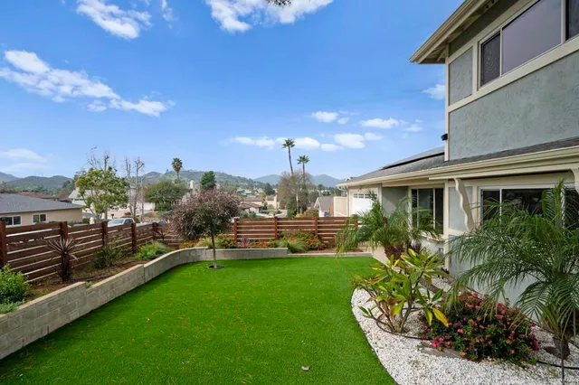 a view of a house with a big yard potted plants and a bench