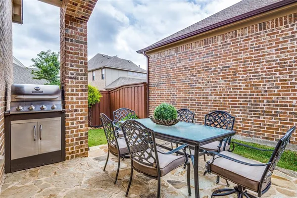 a patio with table and chairs and potted plants