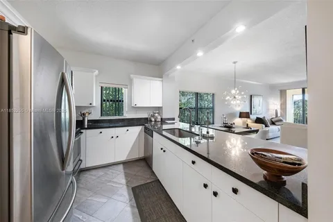a kitchen with granite countertop a sink a stove top oven a counter space and cabinets