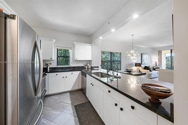 a kitchen with granite countertop a sink a stove top oven a counter space and cabinets