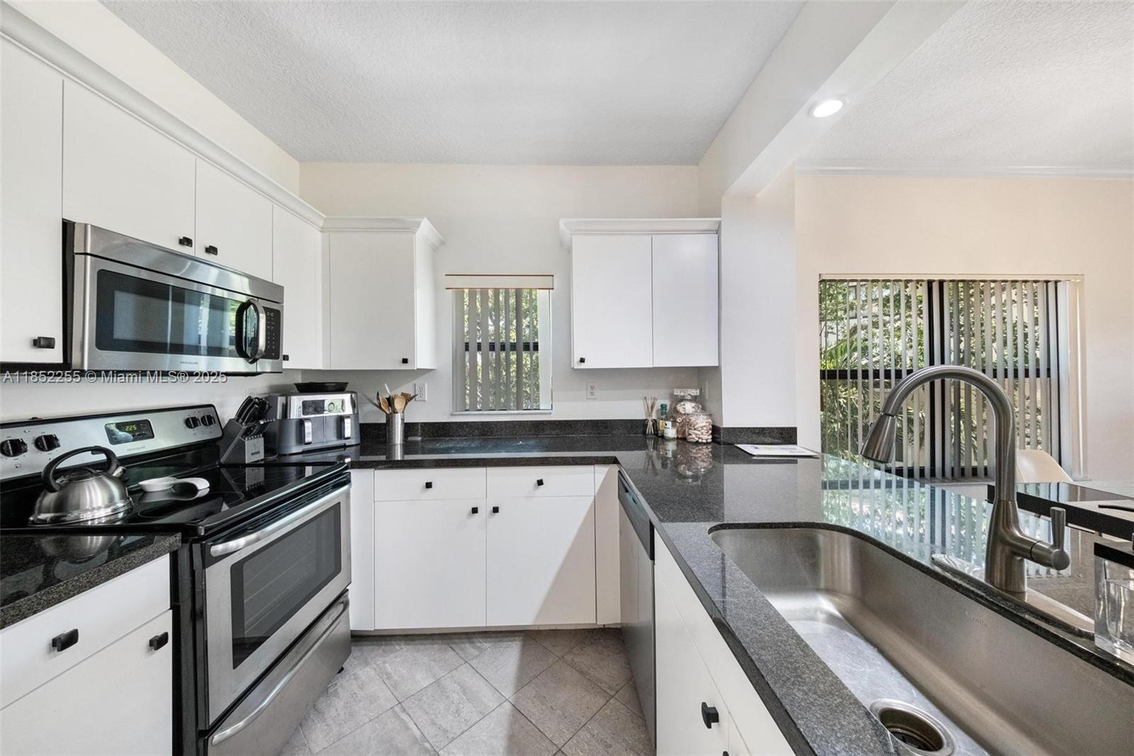 800 Uno Lago Drive, Unit 301 Juno Beach, FL 33408 - Photo 8 of 27 a kitchen with granite countertop a sink a stove top oven a counter space and cabinets
